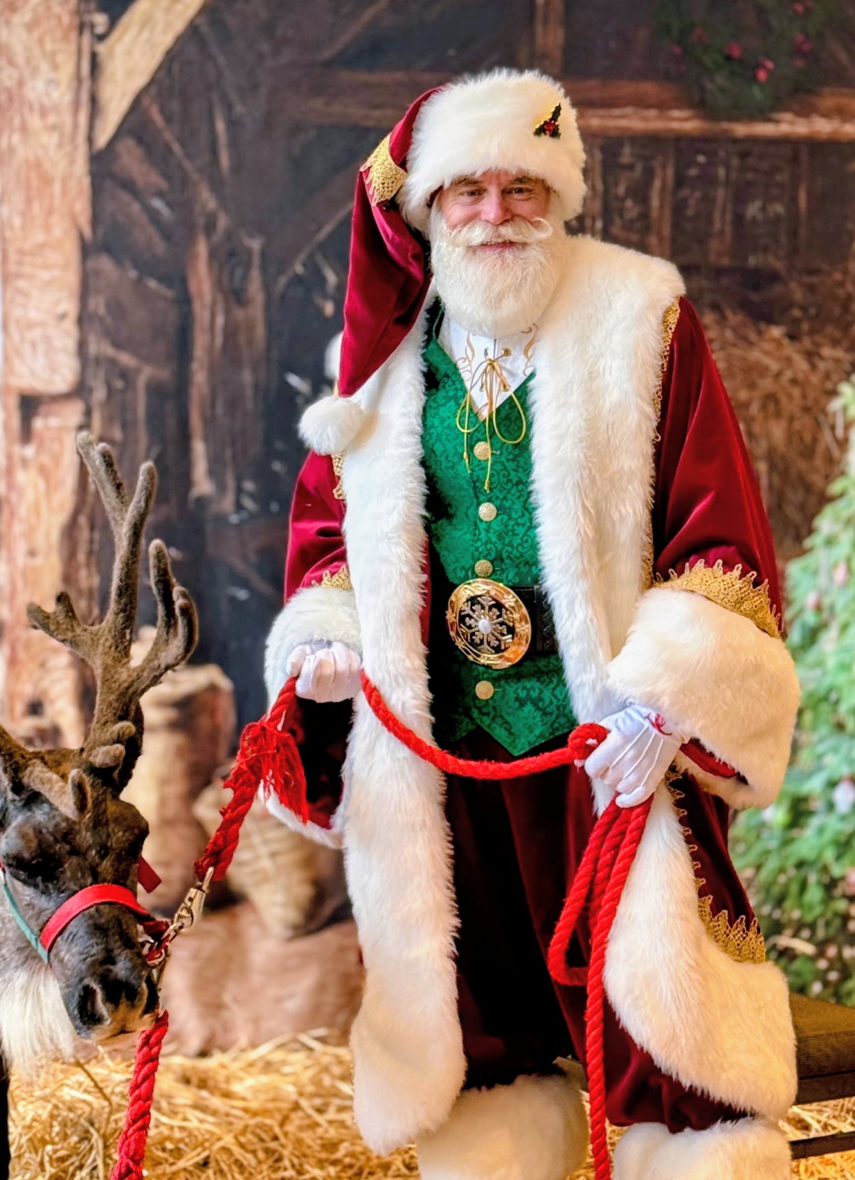 Santa in a traditional red suit beside a reindeer