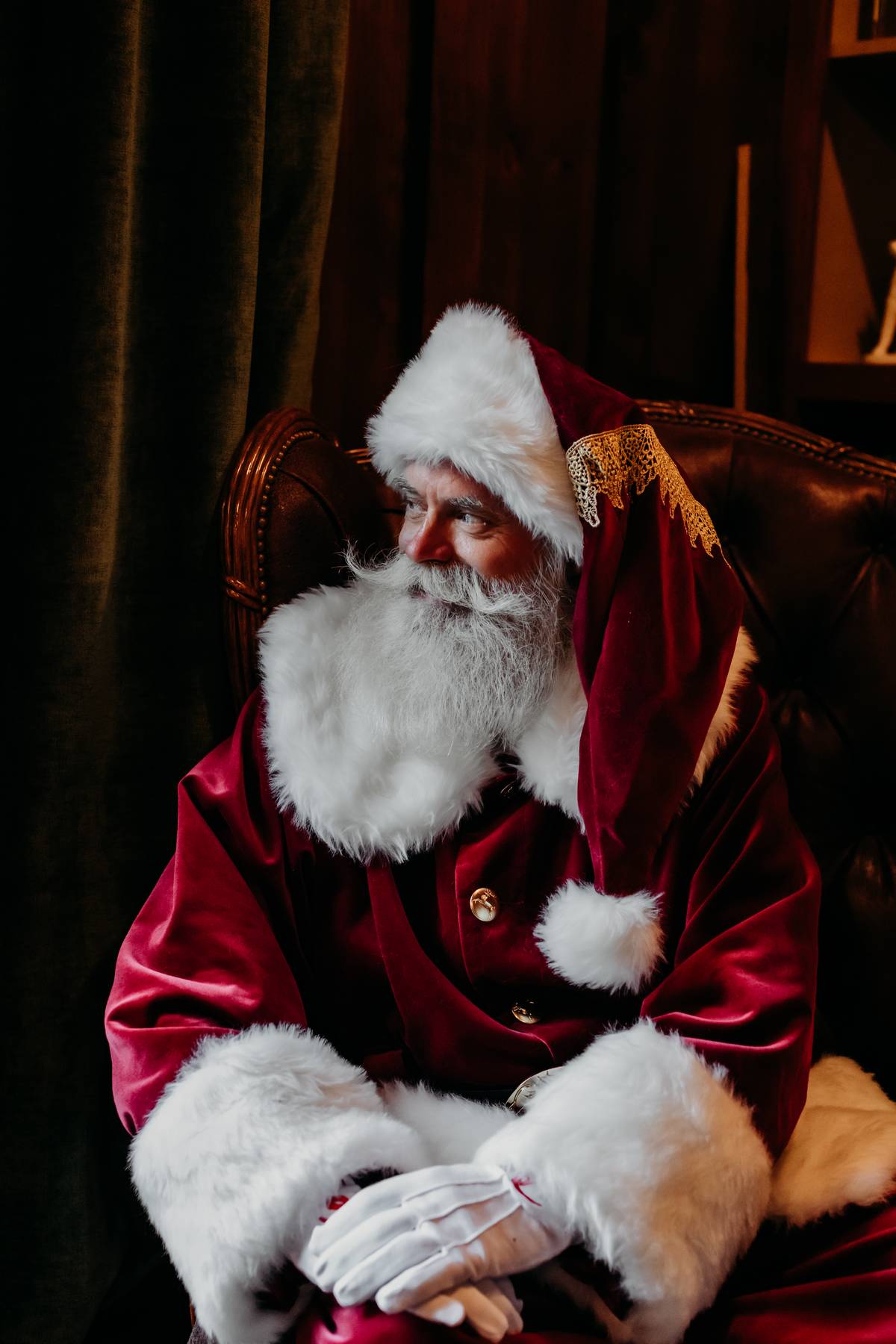 The Dapper Santa seated in a classic leather chair